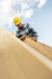 Worker With Hard Hat Level Checking Roof Timber House